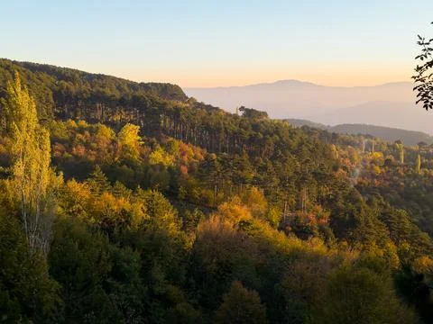 Golden sunset casting warm hues over distant mountains and valleys in a ser.. Stock Photos