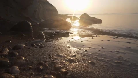 Golden sunset casting warm light over a peaceful rocky beach Stock Footage 337417737
