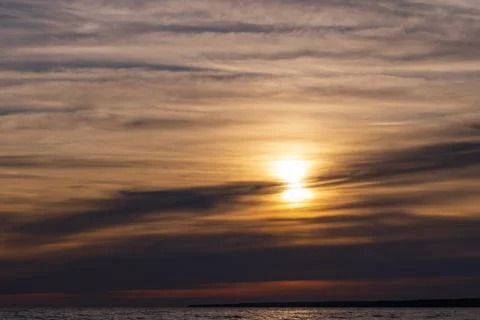 Golden sunset casts warm light across a calm sea Stock Photos