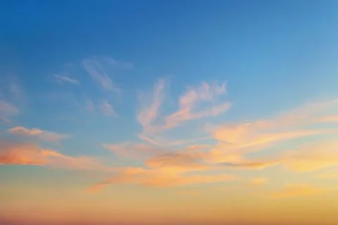 Golden sunset clouds in a clear blue sky. Scenic dusk skyscape. Stock Photos