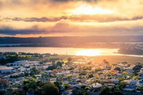 Golden sunset in a cloudy sky reflected in the clam waters of Auckland Harbou Stock Photos