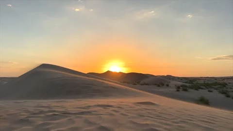 Golden sunset glows over desert dunes, soft orange light spreads across the sky Stock-Footage 288632061