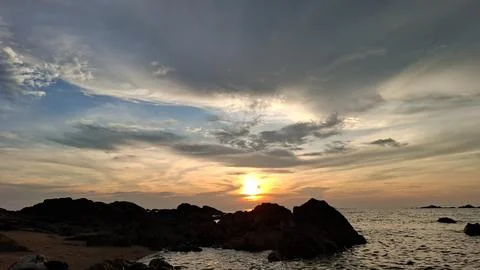 Golden Sunset Horizon with Dramatic Clouds and Rocky Coastal View Stock Photos