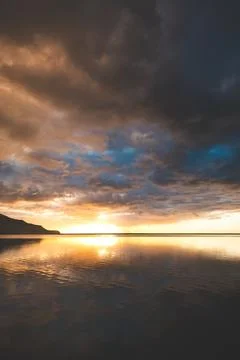 Golden sunset illuminates dramatic clouds above calm water in Iceland Fotos de archivo