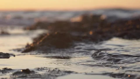 Golden sunset light gently reflects over calm rippling ocean water Stock Footage 337416023