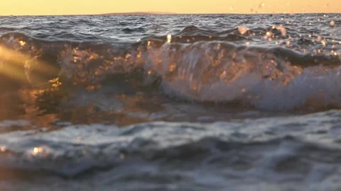 Golden sunset light illuminates gentle crashing ocean wave near shore. Stock Footage 337409857