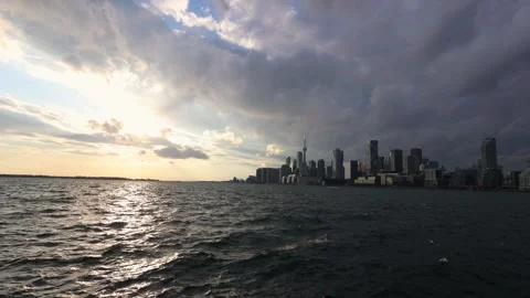 Golden sunset light illuminating dark storm clouds over the Toronto skyline Stock Footage 296596524