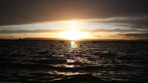 Golden sunset light over moving water with dramatic clouds and calm reflections Stock Footage 328286569