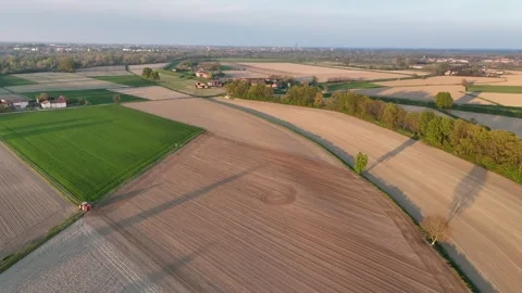Golden sunset light over patchwork of green and brown fields near Po River Stock Footage 308188179