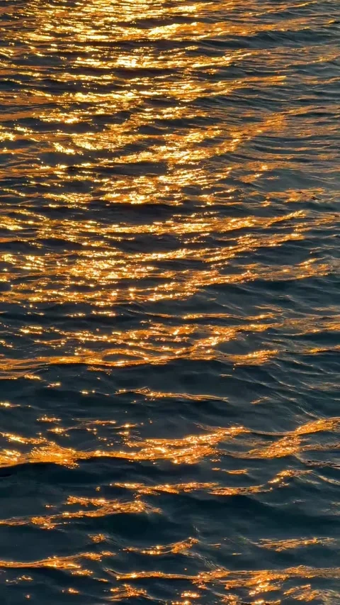 Golden sunset light reflecting on rippling sea water surface. Shimmering waves Stock Footage 346230187