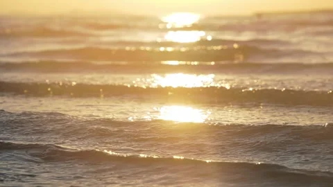 Golden sunset light reflects brightly on gentle calm ocean waves Stock Footage 337410191