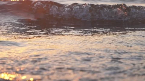 Golden sunset light reflects over calm rippling ocean water waves Stock Footage 337416299
