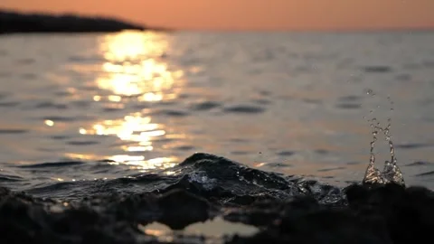 Golden sunset light shimmers over water splash and rocky coast. Stock Footage 337406911