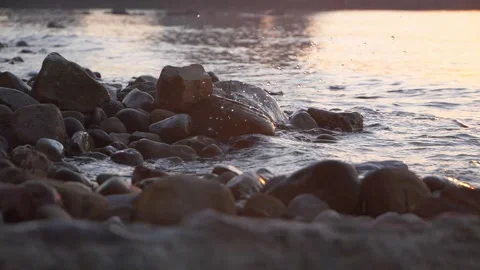 Golden sunset light shimmers softly over wet pebbles on beach. Stock Footage 337406991