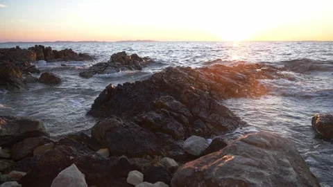 Golden sunset light shining over dark rocky ocean coastline waves. Stock Footage 337408834