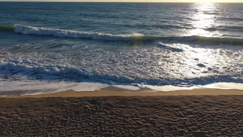 Golden sunset ocean waves rolling gently onto sandy beach shoreline Stock Footage 328142841