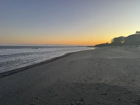 Golden Sunset Over Empty Sandy Beach and Calm Ocean Horizon Stock Photos