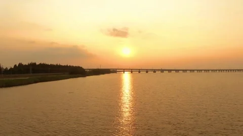 Golden sunset over a long bridge crossing a calm lake during late evening Video stock 342119313