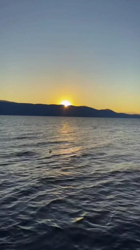 Golden Sunset over Mountain Range and Rippling Lake Stock Footage 328966244