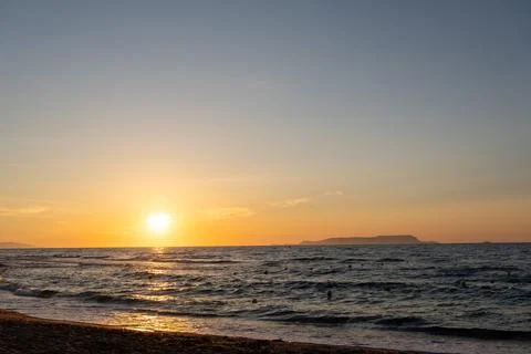 Golden sunset over ocean with distant island and sun path Stock Photos
