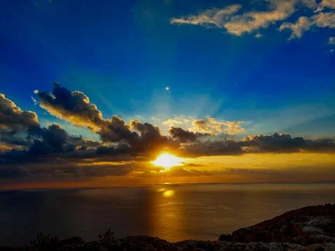Golden Sunset Over the Ocean with Dramatic Clouds Stock Photos