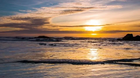 Golden sunset over ocean waves crashing on rocky beach landscape Stock Footage 342138995