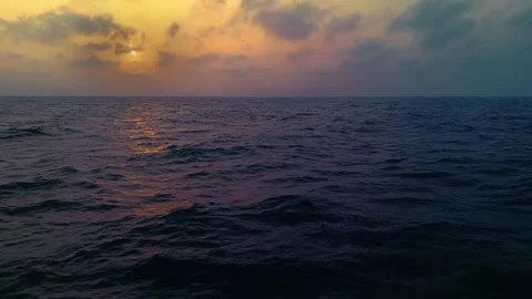 Golden sunset over the open ocean with dramatic clouds and gentle waves Stock Footage 341110861