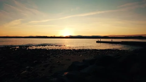 Golden sunset over sandy beach with people in silhouette stock footage Stock Footage 313522211