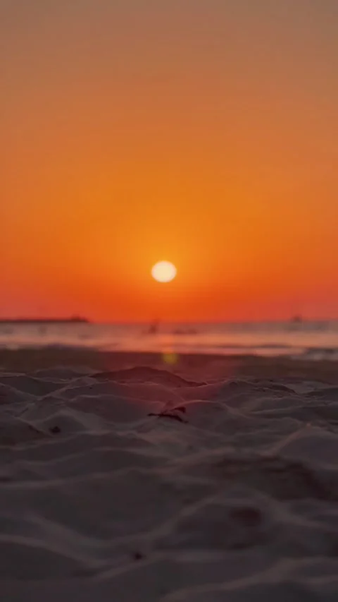 Golden Sunset Over a Tranquil Beach With People Bathing in the Background Stock Footage 338034336