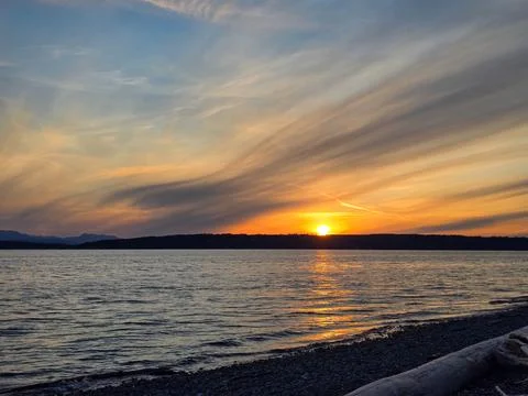Golden Sunset Over Water With Dramatic Streaked Clouds Stock Photos