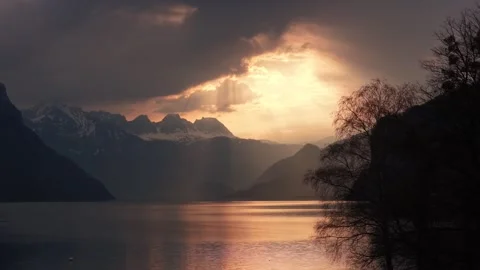 Golden sunset rays over alpine lake and snowy peaks Switzerland Video stock 337788112