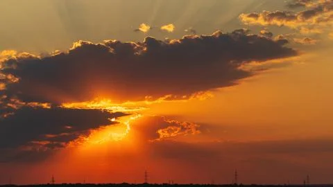 Golden sunset rays shining past dark cloud edges over horizon Stock Photos