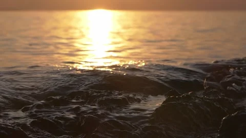 Golden sunset reflecting brightly over calm ocean water and rocks Stock Footage 337405108