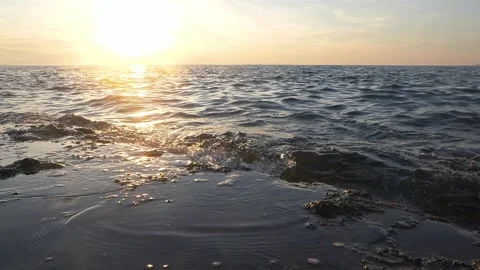 Golden sunset reflecting brightly over ocean waves and dark rocks. Stock Footage 337418320