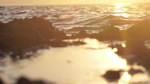 Golden sunset reflecting over calm ocean waves and coastal rocks Stock Footage 337408977