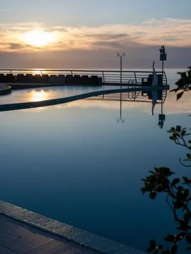 Golden Sunset Reflection in Luxury Infinity Pool. Stock Photos