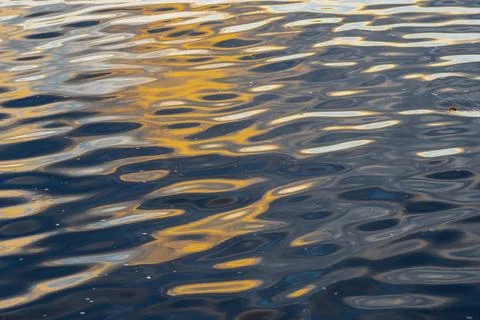 Golden sunset reflection patterns on rippled water surface in Riga Stock Photos