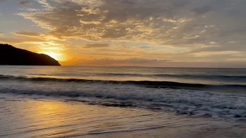 Golden Sunset Reflection on Wet Beach Sand with Silhouetted Coastal Hills 스톡 동영상 320605070