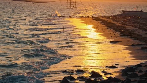 Golden Sunset Reflection on Wet Beach Sand with Gentle Waves and Dark Rocks Stock Footage 332039951