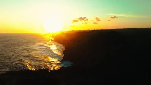 Golden sunset reflects across rolling ocean waves beside the dark tropical .. Stock Footage 341547711