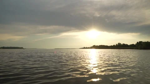 Golden sunset reflects on tranquil river, soft clouds and tree-lined horizon Stock Footage 320402771