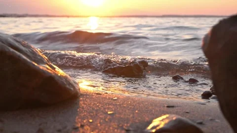 Golden sunset shining over calm ocean waves and rocky beach Stock Footage 337419005