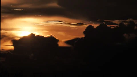 Golden sunset sun setting behind dark silhouetted cumulus clouds, time-lapse Stock Footage 346162455