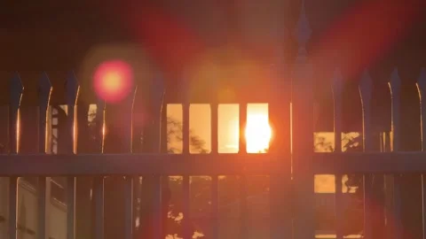 Golden sunset sunlight rays shining through metal security fence. Private Stock Footage 341543245