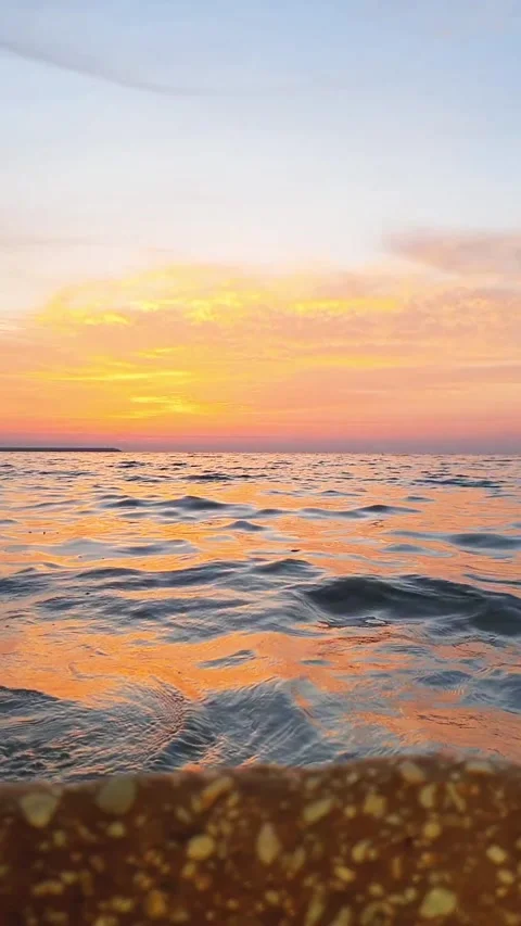 Golden sunset view with the ocean waves hitting the stones on the beach Stock Footage 264963302