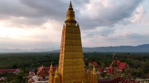 Golden temple complex of Wat Bang Thong at sunset, surrounded by lush vegetation Stock-Footage 313925695