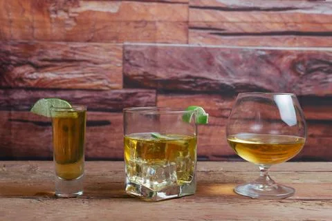 Golden tequila served in different types of shot glasses Stock Photos