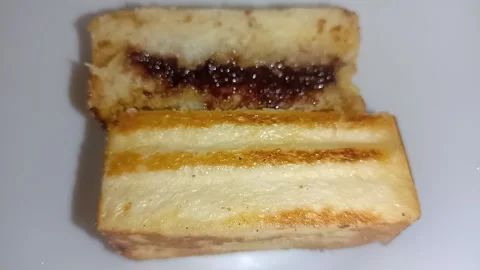 Golden toasted bread slice topped with rich melted chocolate on white background Stock Footage 344425027