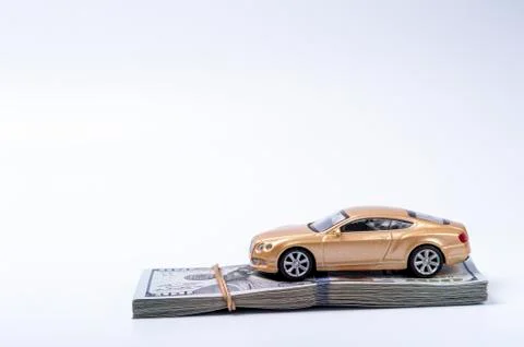 Golden toy car on dollars stack with rubberband Foto stock