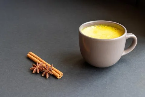 Golden (turmeric) milk in a gray cup on the dark background. Stock Photos